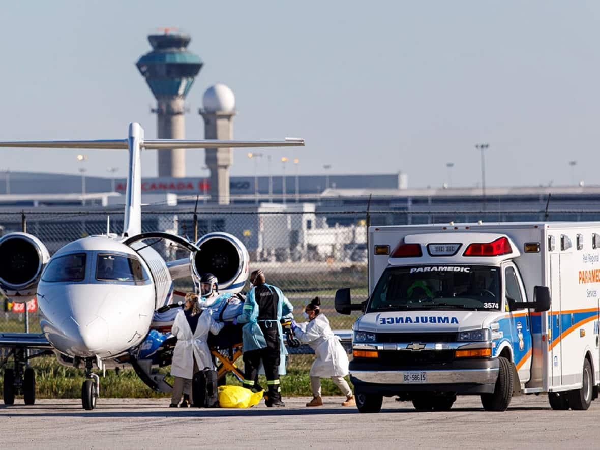 A patient from Saskatchewan is transferred from an air ambulance to a waiting Peel Region ambulance, at Pearson airport in Toronto, on Tuesday. The Ontario Critical Care COVID Command Centre is transporting COVID-19 patients to Ontario ICUs to alleviate strain on the Saskatchewan health-care system. (Evan Mitsui/CBC - image credit)