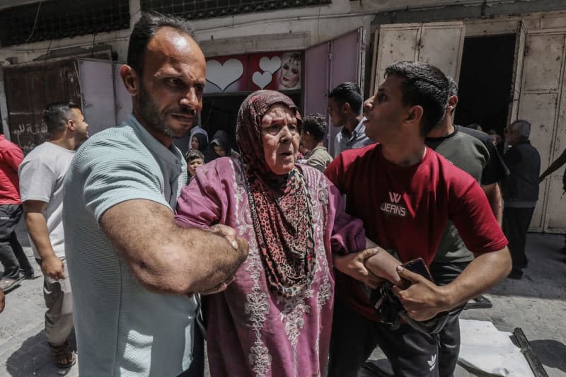 Palestinians help an old woman around after the Israeli bombing of a populated residential building in Nuseirat. Omar Naaman/dpa