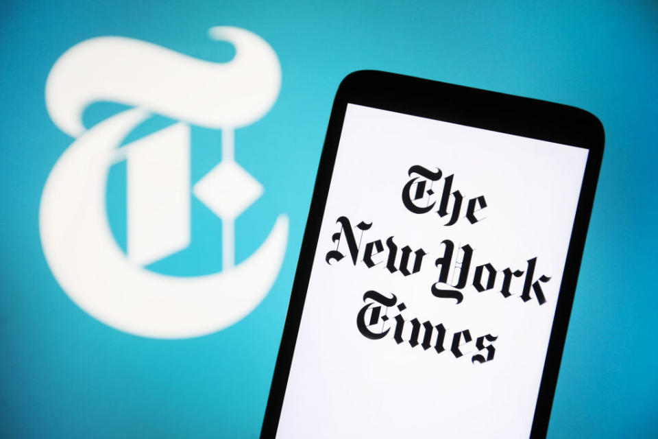 Smartphone screen displaying "The New York Times" with the newspaper's logo in the background