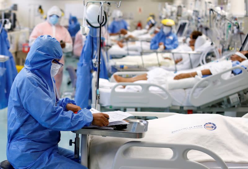 Un trabajador de la salud toma notas cerca de un paciente en la Unidad de Cuidados Intensivos del hospital Villa El Salvador durante el brote de coronavirus, en Lima, Perú