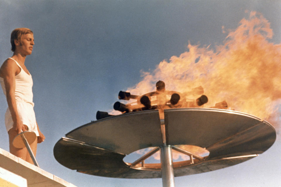 Runner Guenther Zahn stands near the Olympic flame he lit above the Olympic Stadium on Aug. 26, 1972, during the opening ceremony of the Summer Olympic Games in Munich, Germany. (AP Photo)