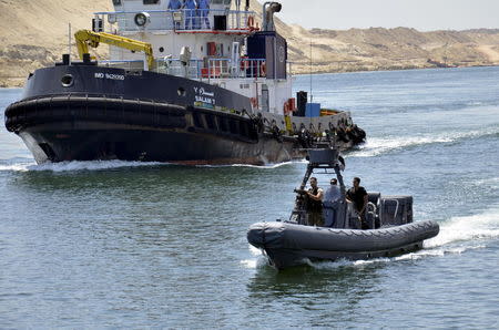 Security personnel are seen near a cargo ship crossing through the New Suez Canal, Ismailia, Egypt, July 25, 2015. REUTERS/Stringer