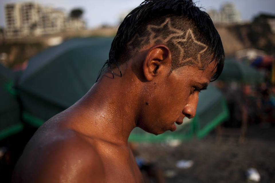 In this March 3, 2013 photo, Giovani Camargo dries off after a swim in the waters of Agua Dulce beach in Lima, Peru. While Lima's elite spends its summer weekends in gate beach enclaves south of the Peruvian capital, the working class jams by the thousands on a single municipal beach of grayish-brown sands and gentle waves. The only barrier to entry to Agua Dulce beach is two dollars, the price of bus fare to get there and home. (AP Photo/Rodrigo Abd)