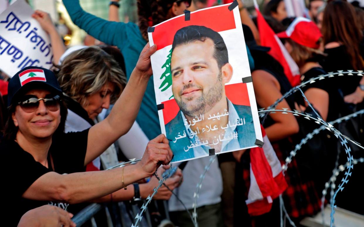 A Lebanese demonstrator carries a portrait of Alaa Abou Fakhr, who was shot dead south of Beirut - AFP