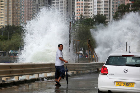 A man looks on while walking in front of big waves along a waterfront as Typhoon Haima approaches in Hong Kong, China, October 21, 2016 . REUTERS/Bobby Yip