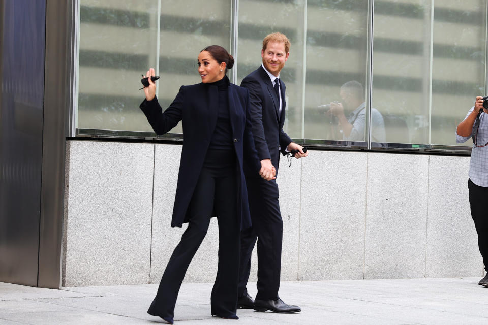 Meghan Markle wore navy Giorgio Armani coat, turtleneck and trousers with navy suede heels from Aquazzura as she waves over her shoulder, with Prince Harry smiling beside her as they visit the One World Observatory as NY Governor Hochul and NYC Mayor Blasio along with them in New York City, United States on September 23, 2021. 