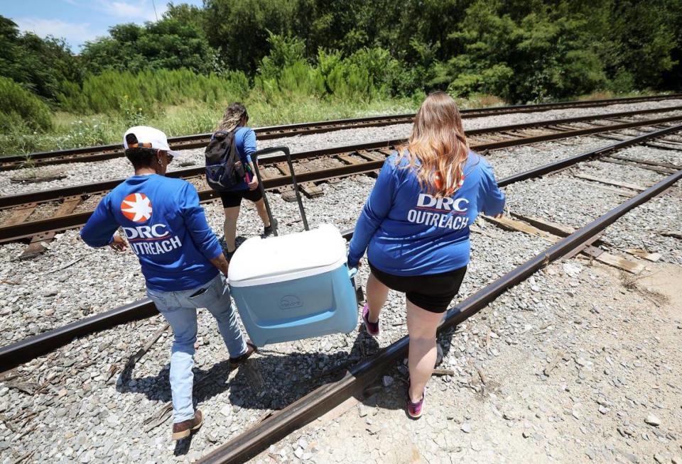 DRC outreach team members Fatimah Robinson, left, Nubia Munoz, center, and Jordan Autry walk to a camp nestled into a wooded area of Fort Worth on Friday, June 30, 2023. During summer months the team carries water, sunscreen, bug repellent and other items that will help unsheltered people cope with Texas’ dangerous heat.