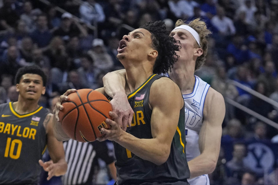 BYU guard Richie Saunders, rear, fouls Baylor guard Miro Little (1) during the first half of an NCAA college basketball game Tuesday, Feb. 20, 2024, in Provo, Utah. (AP Photo/Rick Bowmer)