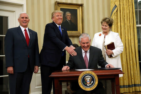 U.S. President Donald Trump reacts during the swearing in ceremony for new U.S. Secretary of State Rex Tillerson (2nd R) accompanied by his wife Renda St. Clair (R) and Vice President Mike Pence at the Oval Office of the White House in Washington, DC, U.S., February 1, 2017. REUTERS/Carlos Barria