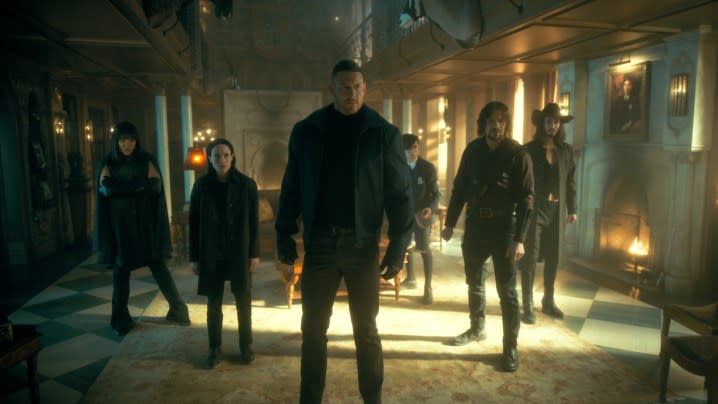 The cast of The Umbrella Academy stands together in the main room of the family mansion.