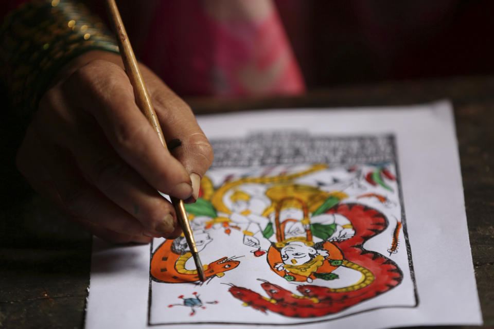 In this July 31, 2019, photo, Tej Kumari Chitrakar makes a traditional painting ahead of Naag Panchami festival at her residence in Bhaktapur, Nepal. Chitrakar families in the Nepalese capital of Kathmandu were renowned traditional painters and sculptors who depicted gods and goddesses on temples, masks of Hindu deities and posters for various religious celebrations. For Tej Kumari and her husband it is a struggle to keep the dying art alive against the modern mass produced prints. (AP Photo/Niranjan Shrestha)