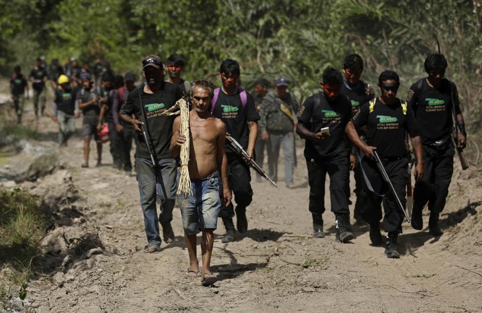 Altemir Freitas Mota carries a tool used in cutting down trees as he leads Tenetehara Indigenous men from the Ka'Azar, or Forest Owners, to his group's campsite after he was apprehended for illegal logging on the Alto Rio Guama reserve in Para state, near the city of Paragominas, Brazil, Tuesday, Sept. 8, 2020. Three Tenetehara Indigenous villages are patrolling to guard against illegal logging, gold mining, ranching, and farming on their lands, as increasing encroachment and lax government enforcement during COVID-19 have forced the tribe to take matters into their own hands. (AP Photo/Eraldo Peres)