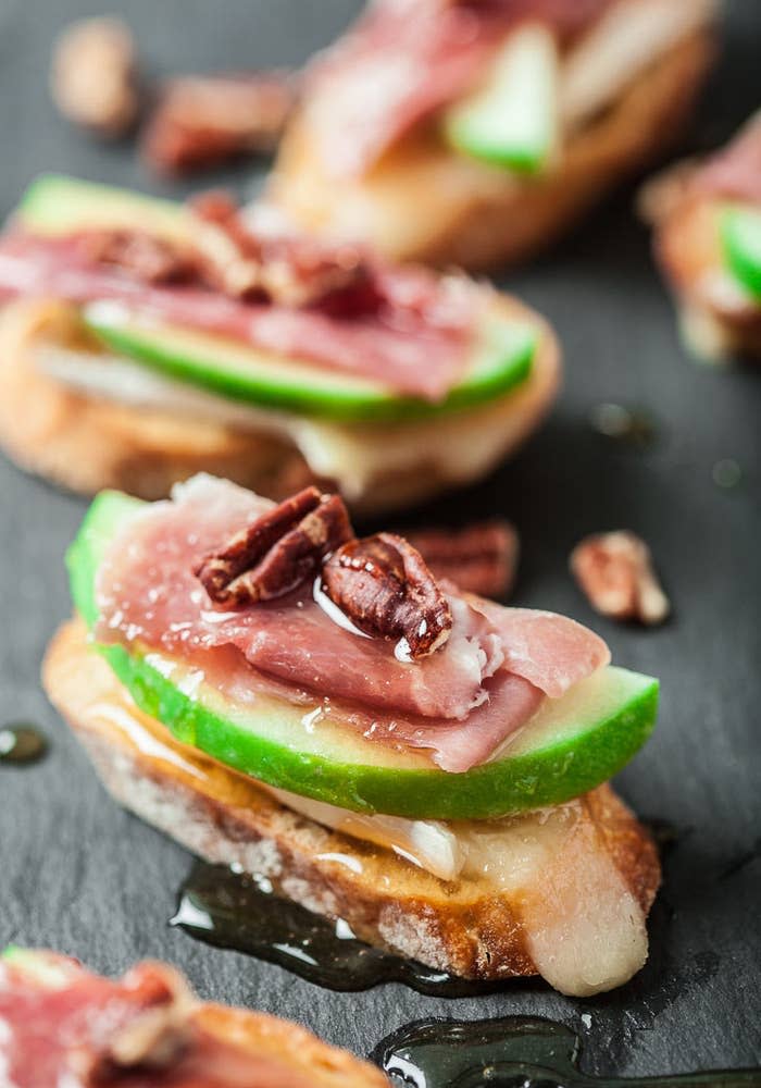 Crostini topped with Brie cheese, prosciutto, and sliced apple.