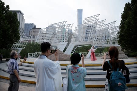 People use mobile devices to record a girl dressed in "Hanfu" dancing at an event marking the traditional Qixi festival at a park in Beijing's central business area, China