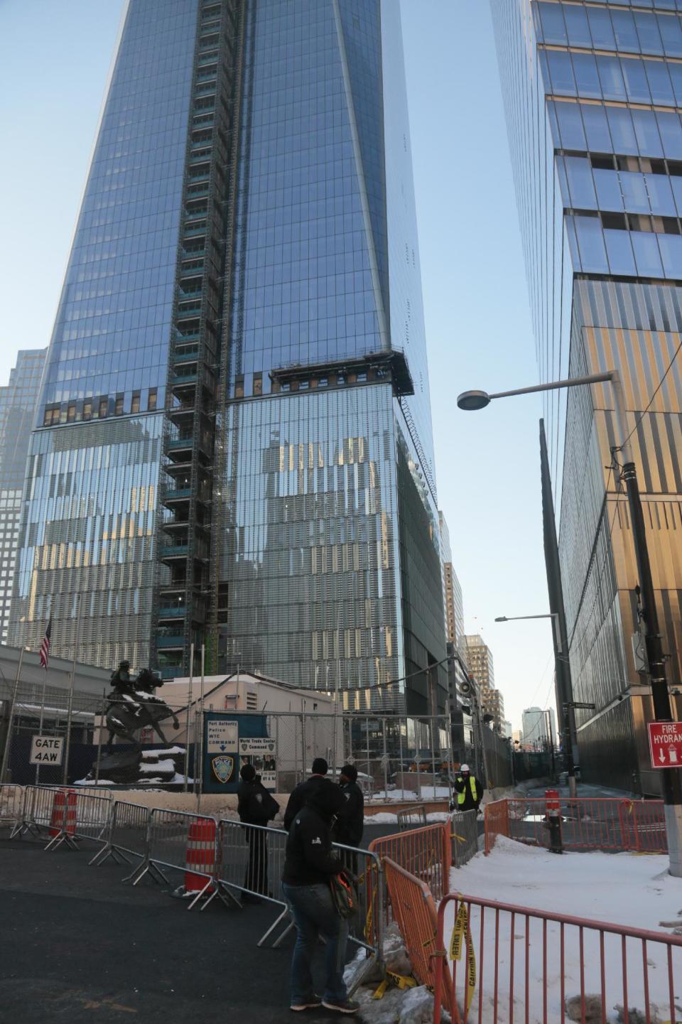 Metropolitan Transit Authority police guard a closed pedestrian walkway next to 1 World Trade Center, left, on Tuesday, Feb. 11, 2014 in New York. The new 1 World Trade Center, the nation's tallest building, was recently cordoned off so pedestrians could avoid injury from falling ice. (AP Photo/Bebeto Matthews)