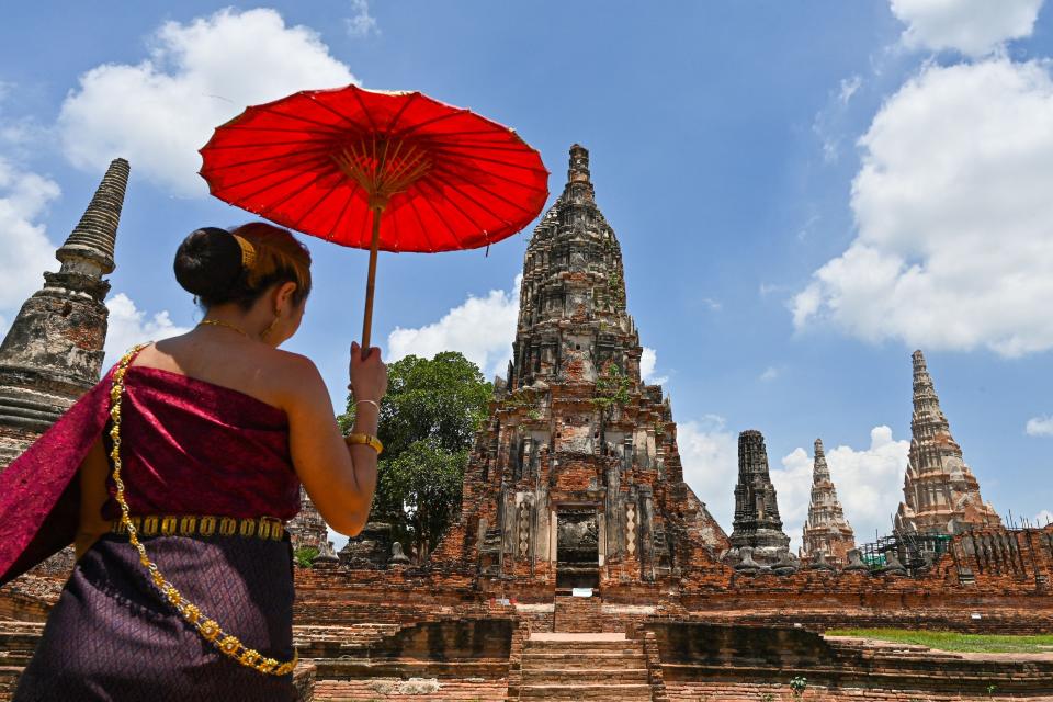 A visitor in traditional attire arrives at the 17th century Wat Chaiwatthanaram temple complex in the ancient capital of Ayutthaya, north of Bangkok, on June 27, 2021.