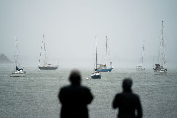 People watch sailboats at Sarasota Bay as Hurricane Ian approaches on September 28, 2022, in Sarasota, Florida.