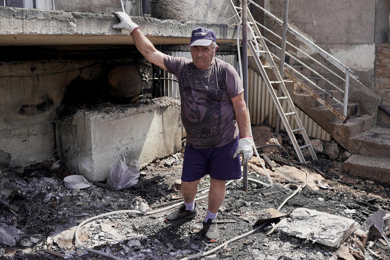 Lazaros Alexandridis, 69, reacts outside his house damaged by wildfire at the settlement of Tsakali 