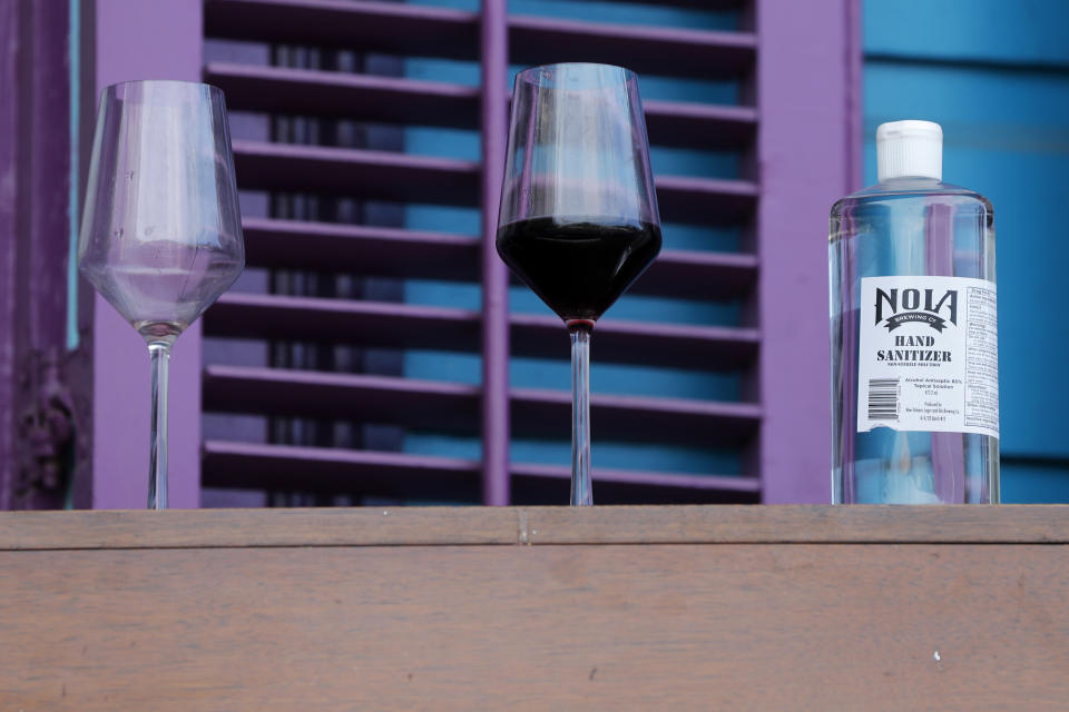 A glass of wine and a bottle of hand sanitizer sit atop a piano on the port of singer Anais St. John after a front porch concert at her home in New Orleans, Saturday, April 11, 2020. With New Orleans music venues shuttered for more than a month now because of the coronavirus outbreak, musicians and fans are finding new places to connect – porches, living rooms, studios and lawns – and reaching their largest audiences online, many streaming performances live on social media platforms. But for the city's club owners awaiting the green light to reopen there's concern about all the uncertainties, like how long it may take tourists to return, how soon the music scene will rebound and when it does, what it will look like. (AP Photo/Gerald Herbert)