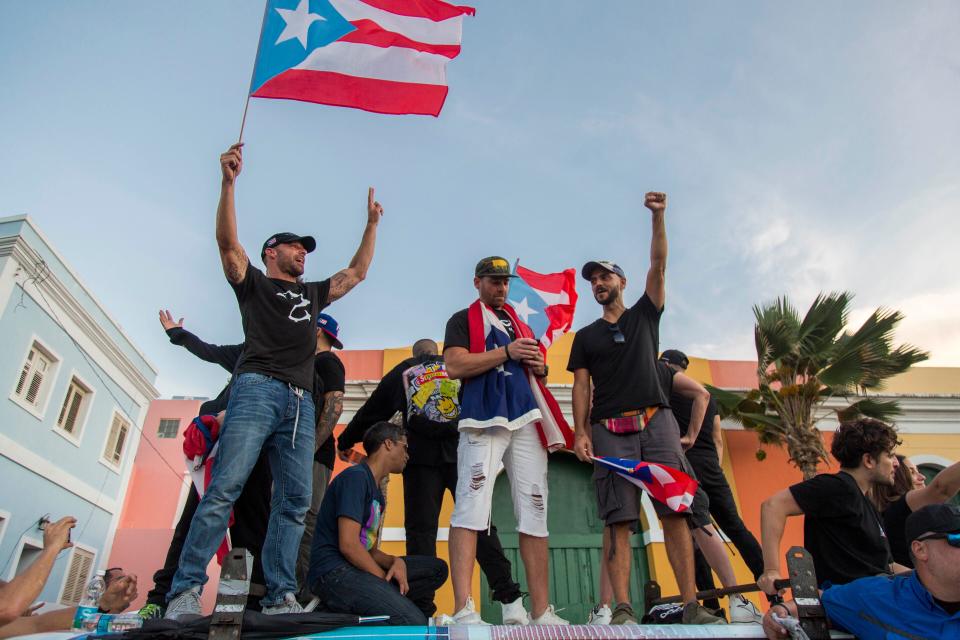 Singer Ricky Martin, left, waves the Puerto Rican flag during march against governor Ricardo Rosello, in San Juan.