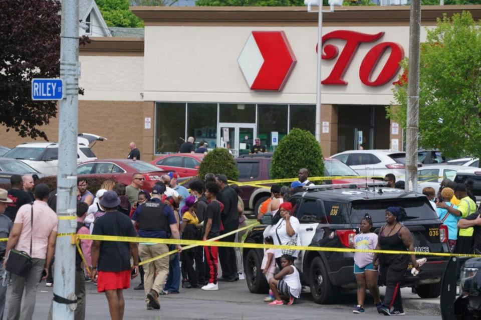 People gather outside a supermarket where several people were killed in a shooting, Saturday, May 14, 2022 in Buffalo, N.Y. Officials said the gunman entered the supermarket with a rifle and opened fire. Investigators believe the man may have been livestreaming the shooting and were looking into whether he had posted a manifesto online (Derek Gee/The Buffalo News via AP)