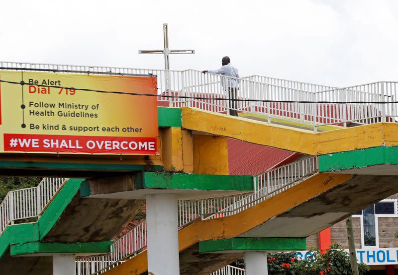 A man looks at a sign hanging from a foot bridge warning against the spread of the coronavirus disease in Nairobi