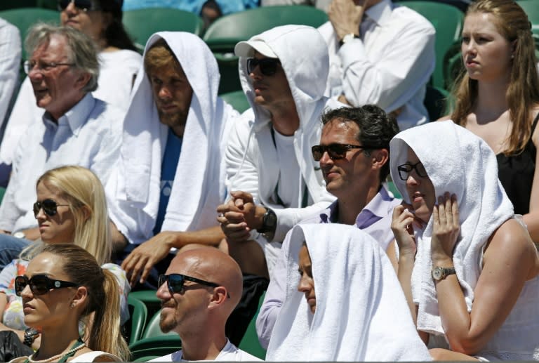 Spectators shield from the sun with towels on day two of Wimbledon on June 30, 2015