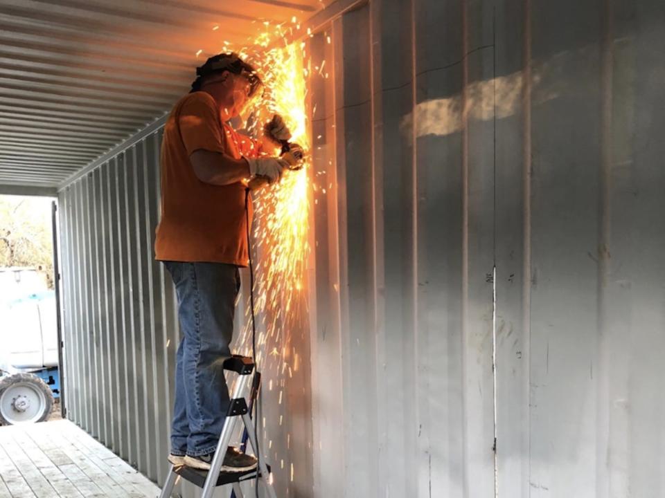 Openings for windows and doors being cut into the walls of the container.