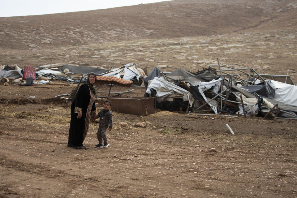 Palestinians walk by destroyed tents in Khirbet Humsu in Jordan Valley in the West Bank, Friday, Nov. 6, 2020. Israeli troops with bulldozers and heavy equipment demolished 18 tents and other structures that housed 74 people, including 41 minors, according to the Israeli rights group B'Tselem. COGAT, the Israeli military body in charge of civilian affairs in the West Bank, said an "enforcement activity" was carried out against seven tents and eight pens that were "illegally constructed" in a firing range. (AP Photo/Majdi Mohammed)