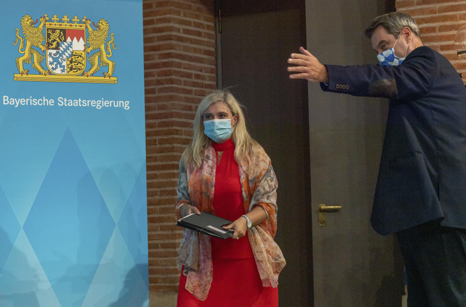 Melanie Huml, Health Minister of the German state of Bavaria, left, and Bavaria's governor Markus Soeder, right, arrive for a joint press conference in Munich, Germany, Thursday, Aug. 13, 2020. (Peter Kneffel/dpa via AP)