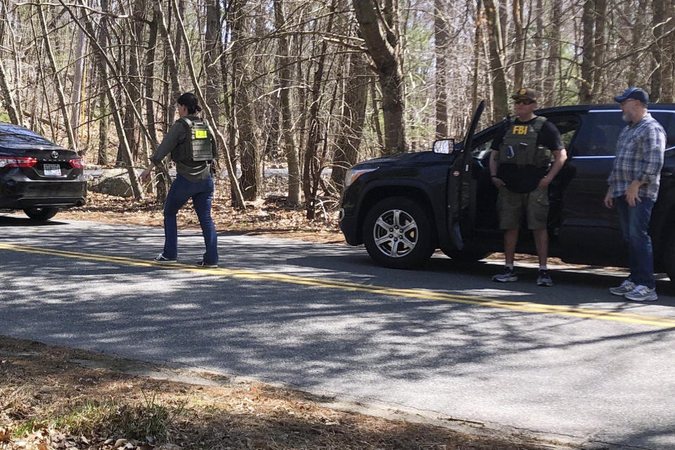 A person in an FBI negotiator vest walks on a road in North Dighton, Mass., Thursday, April 13, 2023. The FBI wants to question a 21-year-old member of the Massachusetts Air National Guard in connection with the disclosure of highly classified military documents on the Ukraine war, two people familiar with the investigation said. (AP Photo/Jennifer McDermott)