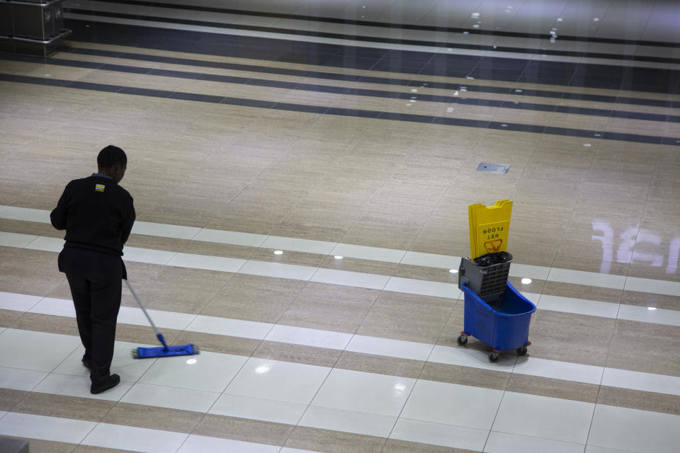A cleaner mops a floor in a Johannesburg supermarket Wednesday, March 18, 2020 as a measure against the new coronavirus. For most people, the new coronavirus causes only mild or moderate symptoms. For some it can cause more severe illness. (AP Photo/Denis Farrell)