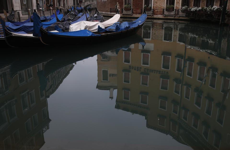 Gondolas are docked in Venice, Italy, Saturday, Jan. 30, 2021. Gondolas and other vessels are moored instead of preparing for Carnival's popular boat parade in the lagoon. Alleys are eerily empty. Venetians and the city's few visitors stroll must be masked in public places, indoors and out, under a nationwide mandate. (AP Photo/Antonio Calanni)