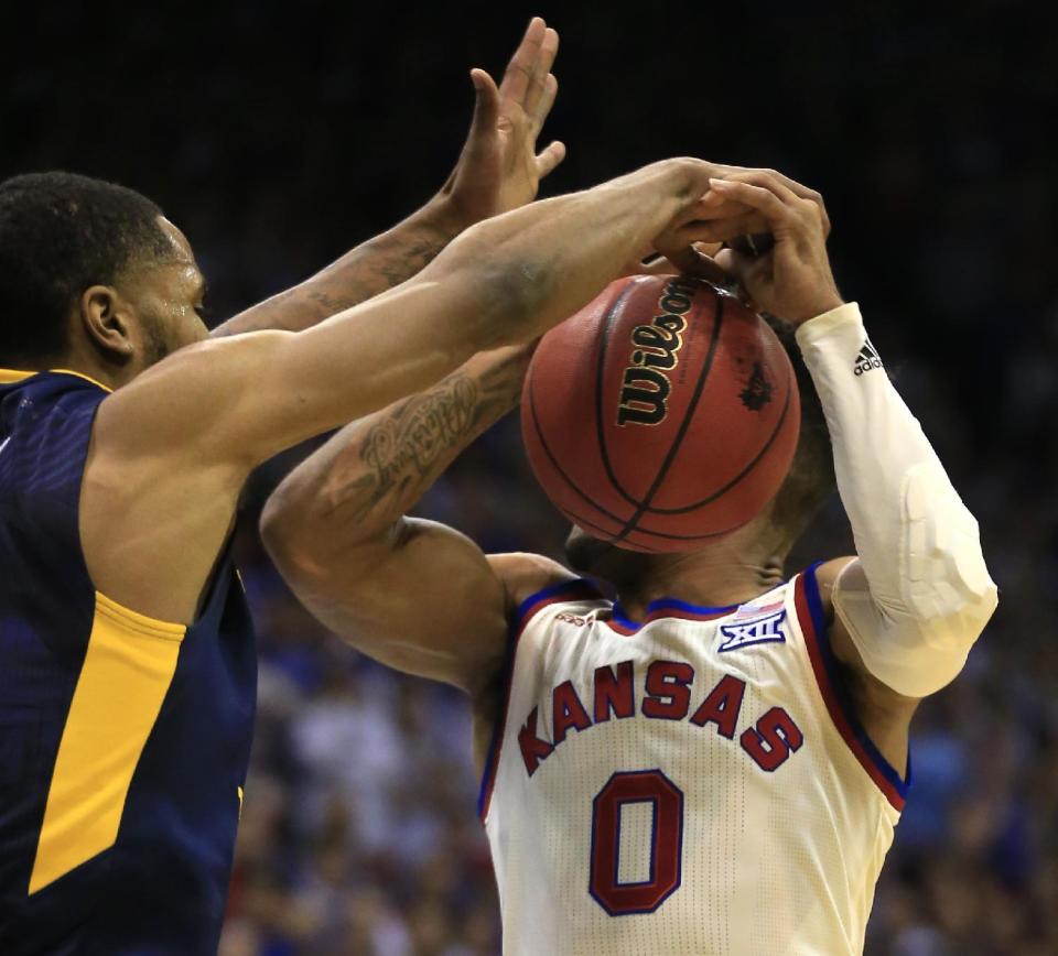 West Virginia guard Tarik Phillip (12) blocks a shot by Kansas guard Frank Mason III (0) during the first half of an NCAA college basketball game in Lawrence, Kan., Monday, Feb. 13, 2017. (AP Photo/Orlin Wagner)