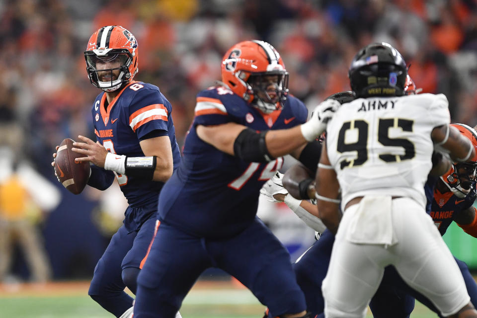 Syracuse quarterback Garrett Shrader, left, looks to pass as offensive lineman Jakob Bradford (74) blocks Army defensive lineman Kyle Lewis (95) during the first half of an NCAA college football game in Syracuse, N.Y., Saturday, Sept. 23, 2023. (AP Photo/Adrian Kraus)