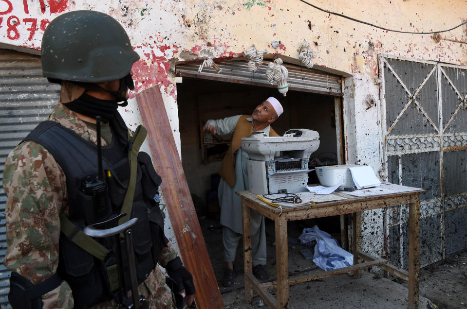 <p>A Pakistani soldier stands guard as a shopkeeper examines damage at the site of a court complex after multiple Taliban suicide bomb attacks in the Tangi area of Charsadda district on February 21, 2017. At least five people were killed when multiple Taliban suicide bombers attacked a court complex in Pakistan on February 21, officials said, the latest in a series of assaults which have raised fears militants are regrouping. (Abdul Majeed /AFP/Getty Images) </p>