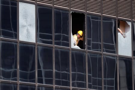 Workers repair windows which were damaged by protestors at the police headquarters in Hong Kong