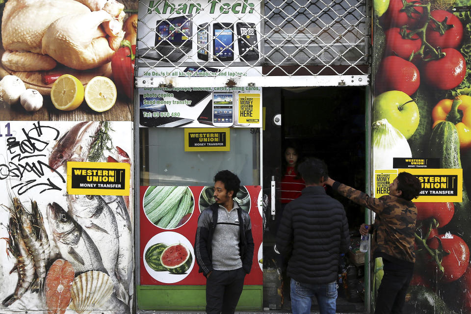 In this Tuesday, Nov. 20, 2018, migrants stand outside of a shop in central Nicosia, Cyprus. The Cyprus Refugee Council, a nonprofit group, said there’s now a backlog of about 8,000 asylum applications as of late 2018, and it takes three to five years to process each claim, including appeals. (AP Photo/Petros Karadjias)