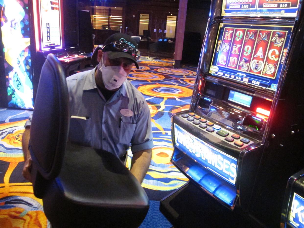 This June 3, 2020, photo shows a worker at the Ocean Casino Resort in Atlantic City, N.J. removing the chair from a slot machine, part of distancing measures to help prevent the spread of the coronavirus. On June 22, New Jersey Gov. Phil Murphy announced that Atlantic City's nine casinos may reopen on July 2 at 25% of capacity.