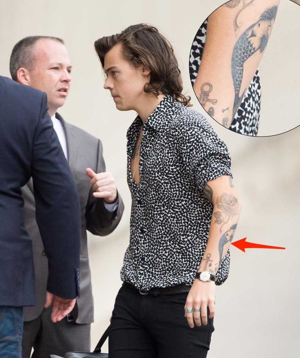 A red arrow pointing to a tattoo of a mermaid on Harry Styles' left arm.