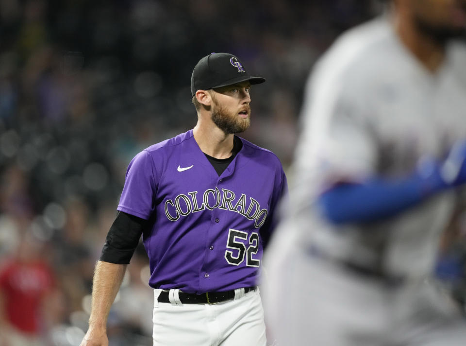 Colorado Rockies relief pitcher Daniel Bard, back, reacts after getting Texas Rangers' Marcus Semien to ground out to end the ninth inning of a baseball game Tuesday, Aug. 23, 2022, in Denver. (AP Photo/David Zalubowski)