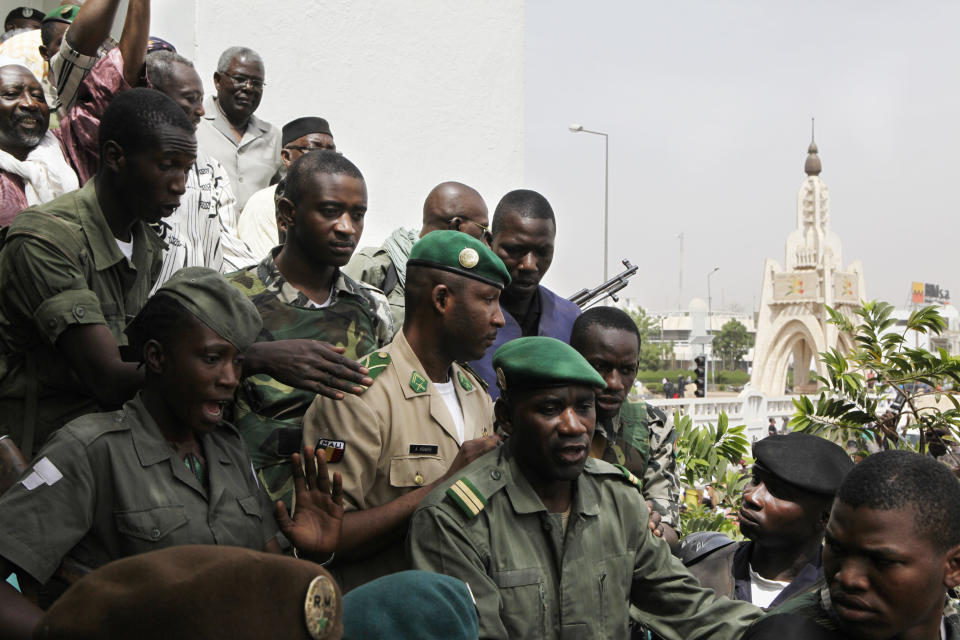 Coup leader Amadou Haya Sanogo, center, in khaki, is surrounded by security as he arrives to address supporters, as thousands rallied in a show of support for the recent military coup, in Bamako, Mali Wednesday, March 28, 2012. The body representing nations in western Africa has suspended Mali and has put a peacekeeping force on standby in the most direct threat yet to the junta that seized control of this nation in a coup last week. (AP Photo/Rebecca Blackwell)