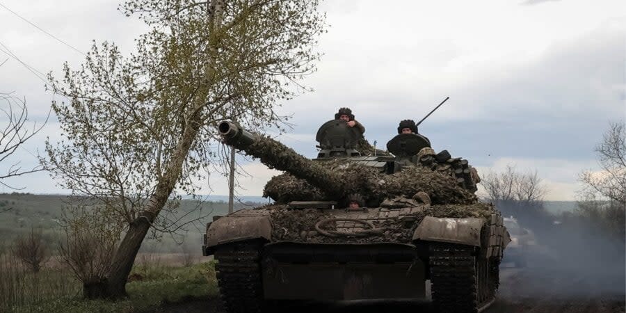 Ukrainian soldiers ride a tank on the road to the town of Chasiv Yar