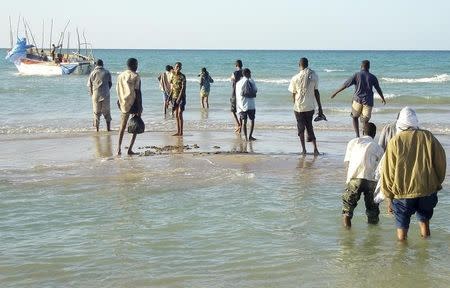 Illegal immigrants from Somalia walk to a vessel in the port town of Bossaso March 13, 2008. REUTERS/Stringer