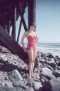 <p>Shirley MacLaine models her swimsuit while standing on the rocks under a pier, circa 1955.</p>