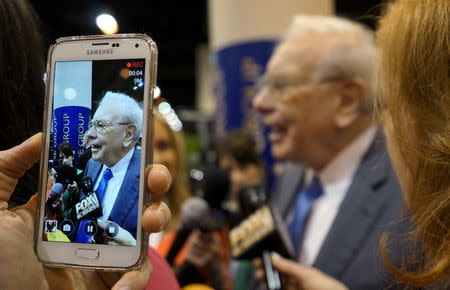 Berkshire Hathaway CEO Warren Buffett is seen on a cellphone camera as he talks to reporters prior to the Berkshire annual meeting in Omaha, Nebraska May 2, 2015. REUTERS/Rick Wilking