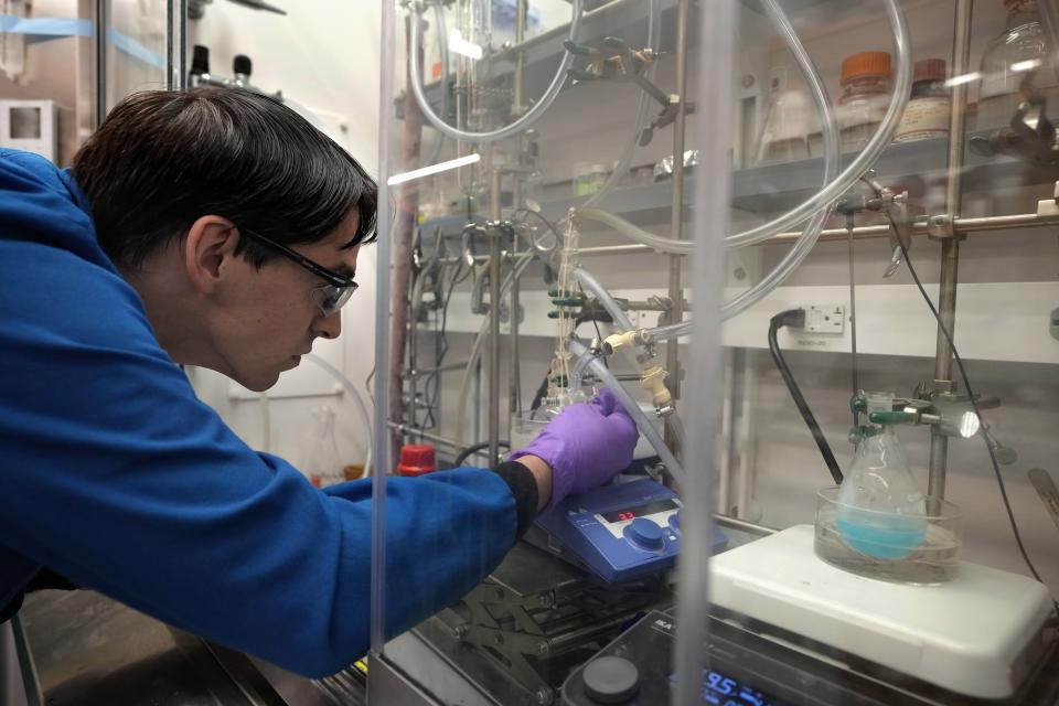 Dan Laorenza, of North Andover, Mass., a post-doctoral researcher at Harvard University, monitors the synthesis of a copper-based candidate for a solid refrigerant in a glass flask, right, in a lab on the school's campus, Thursday, Sept. 14, 2023, in Cambridge, Mass. The process is part of research to develop a more environmentally-friendly solid refrigerant that could be used as an alternative to existing volatile refrigerants. (AP Photo/Steven Senne)