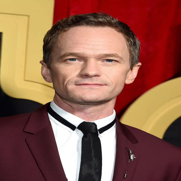 Neil Patrick Harris posing at an event in a dark suit