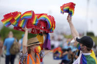 A woman offers LGBT pride flags to football supporters outside of the stadium before the Euro 2020 soccer championship group F match between Germany and Hungary at the Allianz Arena in Munich, Germany, Wednesday, June 23, 2021. (AP Photo/Matthias Schrader)