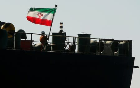 A crew member raises the Iranian flag at Iranian oil tanker Adrian Darya 1, before being named as Grace 1, as it sits anchored after the Supreme Court of the British territory lifted its detention order, in the Strait of Gibraltar
